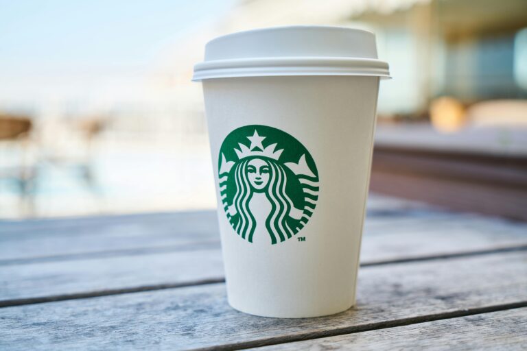 A white coffee cup with a lid on a wooden surface